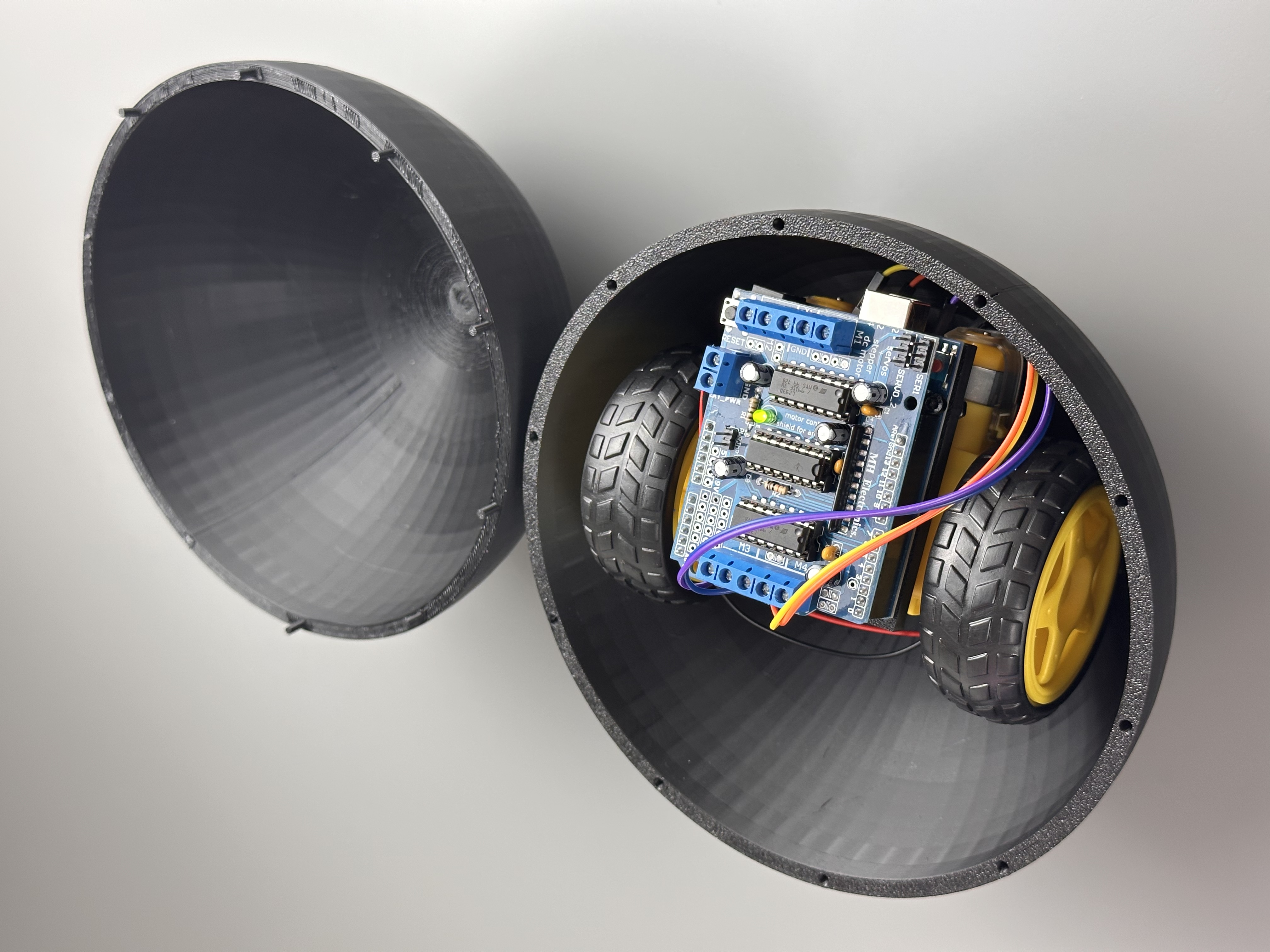 Two separated shell halves showing wheels and electronics inside the lower half