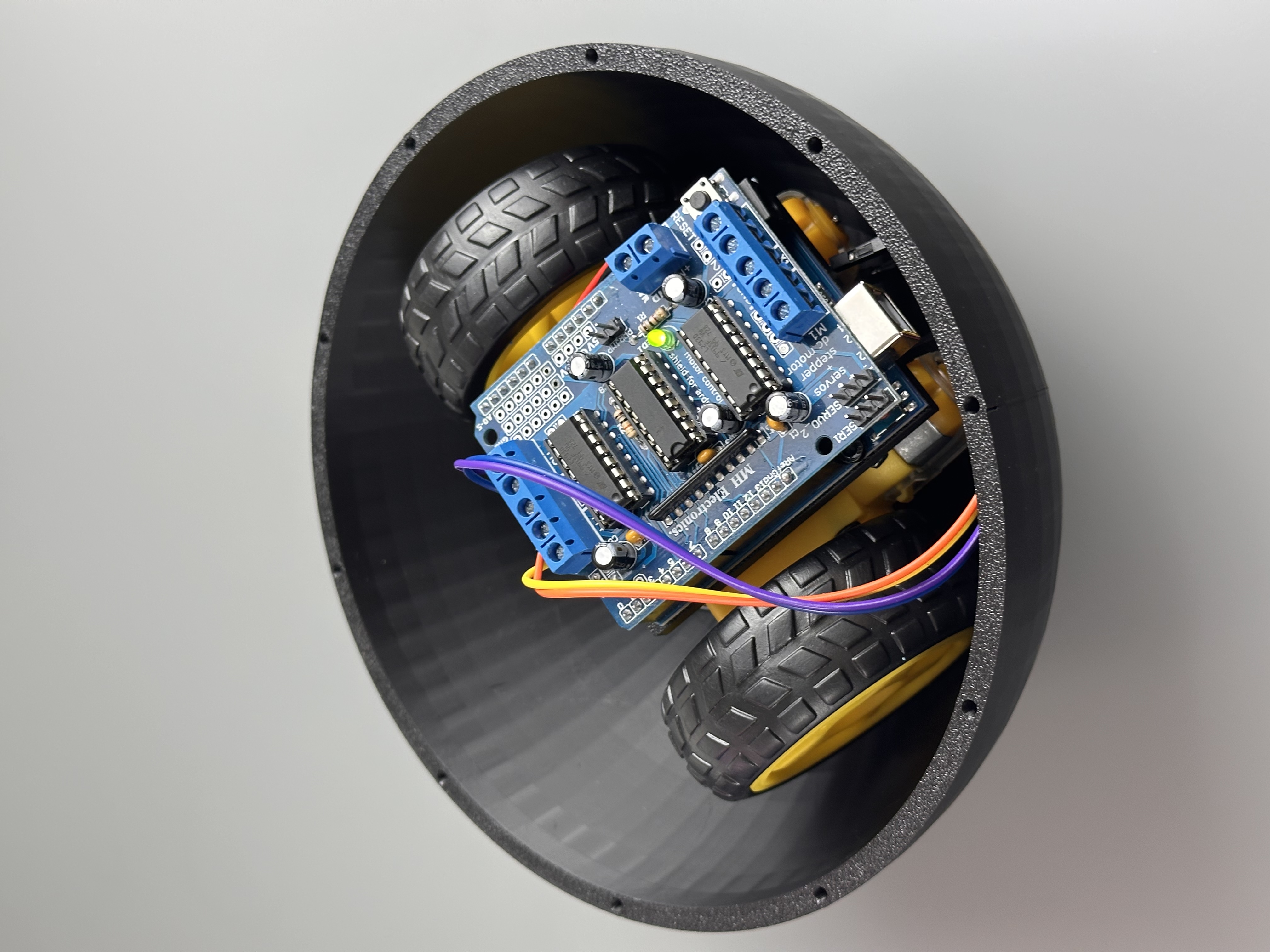 Close view of the circuit board and wheels fitted inside a spherical shell half