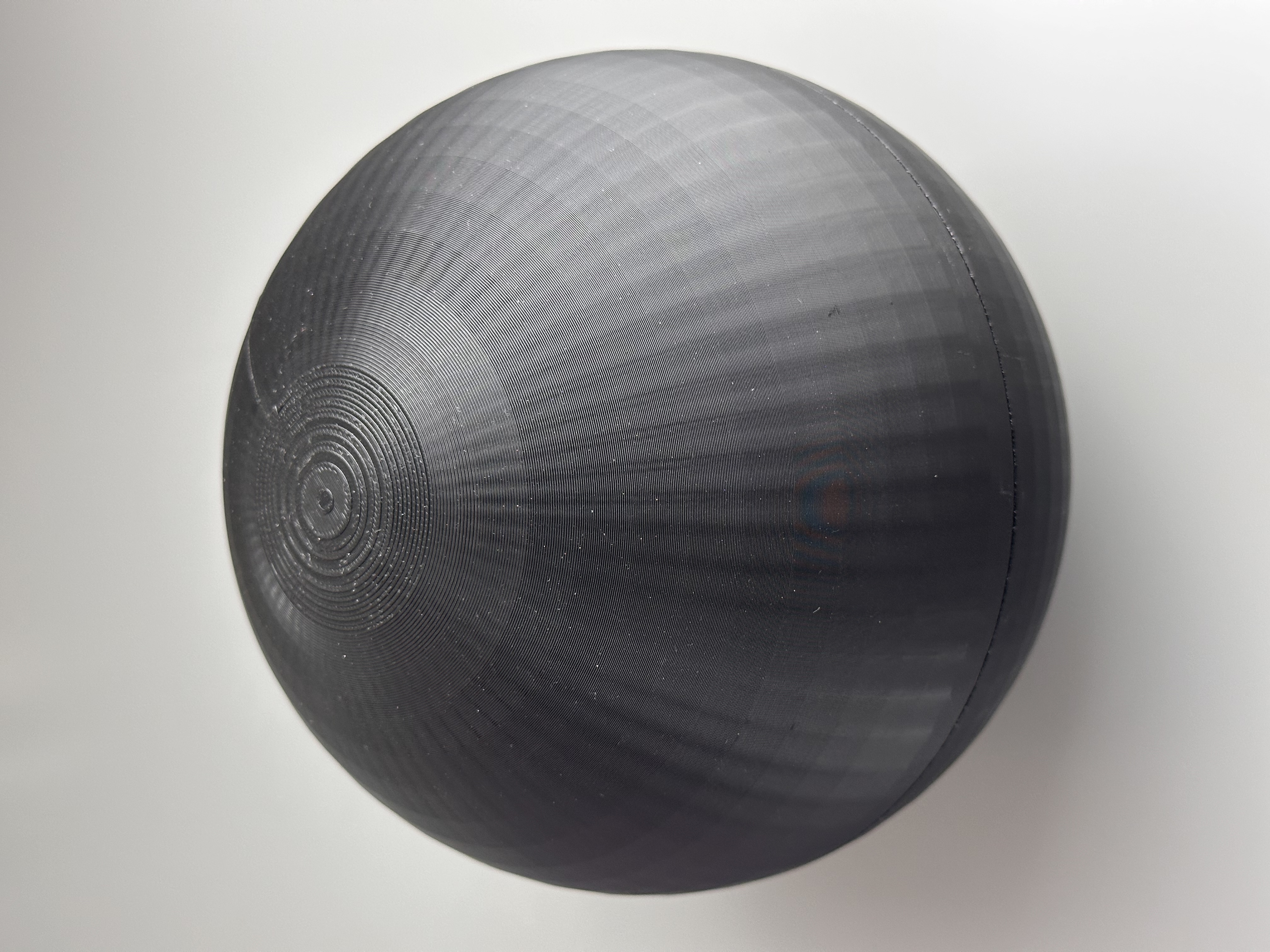 Closed black spherical prototype with visible printed surface texture